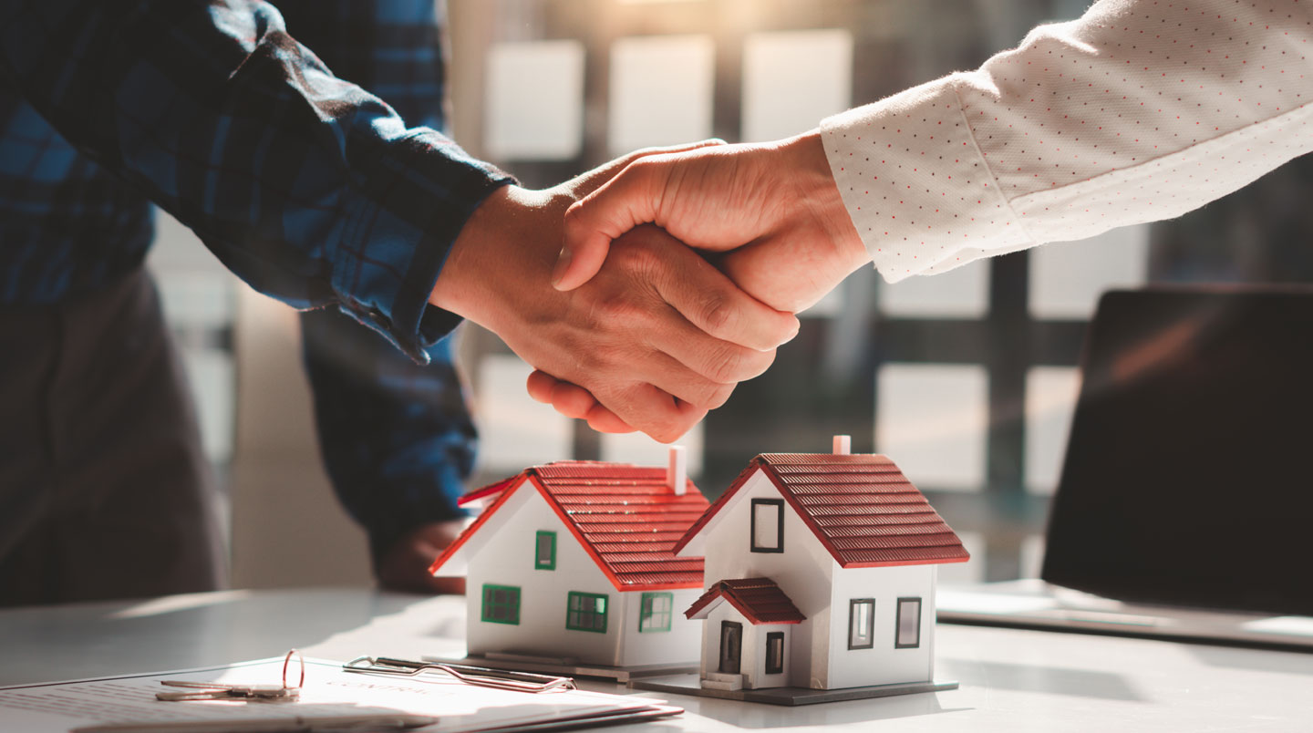 Professionnel immobilier analysant une base de données de transactions immobilières sur écran d'ordinateur dans un bureau d'agence moderne
